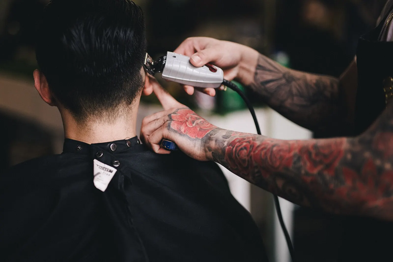 A barber trimming the back of a customer’s head with clippers