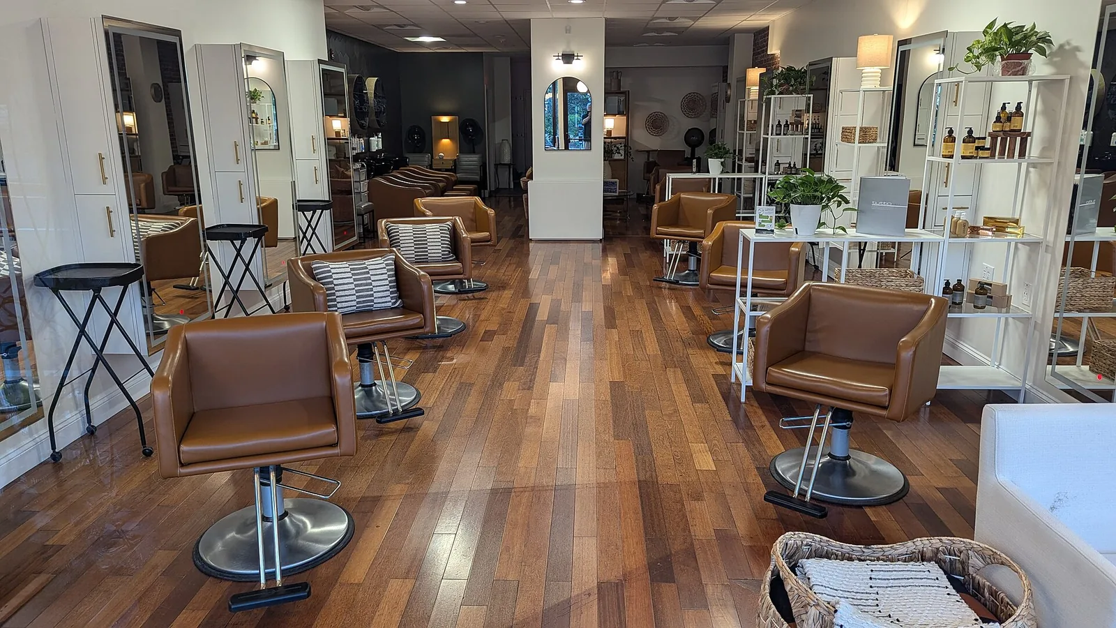 Brown leather chairs facing a row of mirrors, on a wood floor